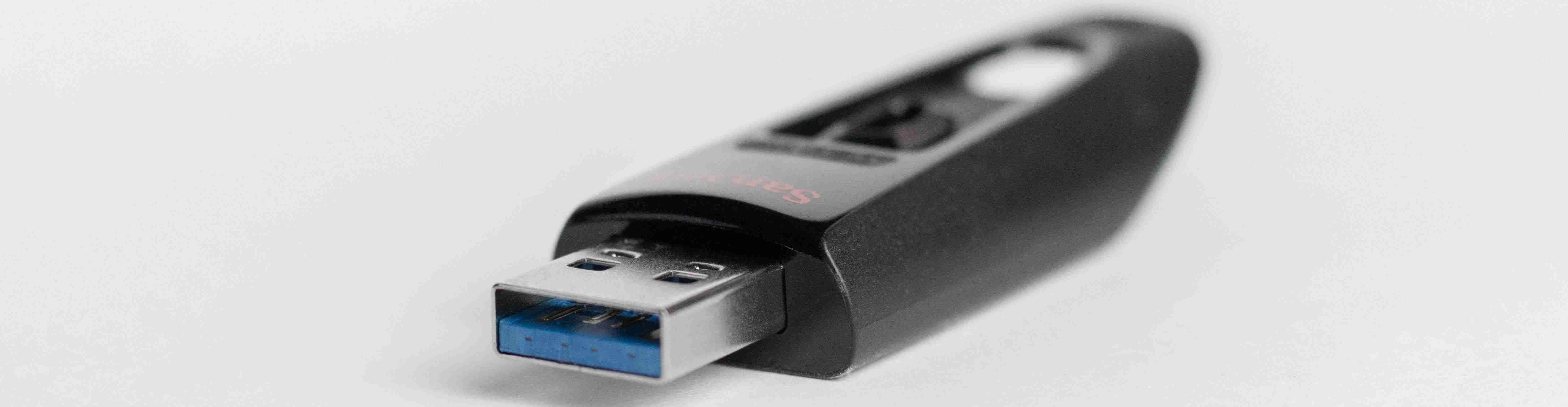A black sandisk USB 3.0 thumb drive with a white background