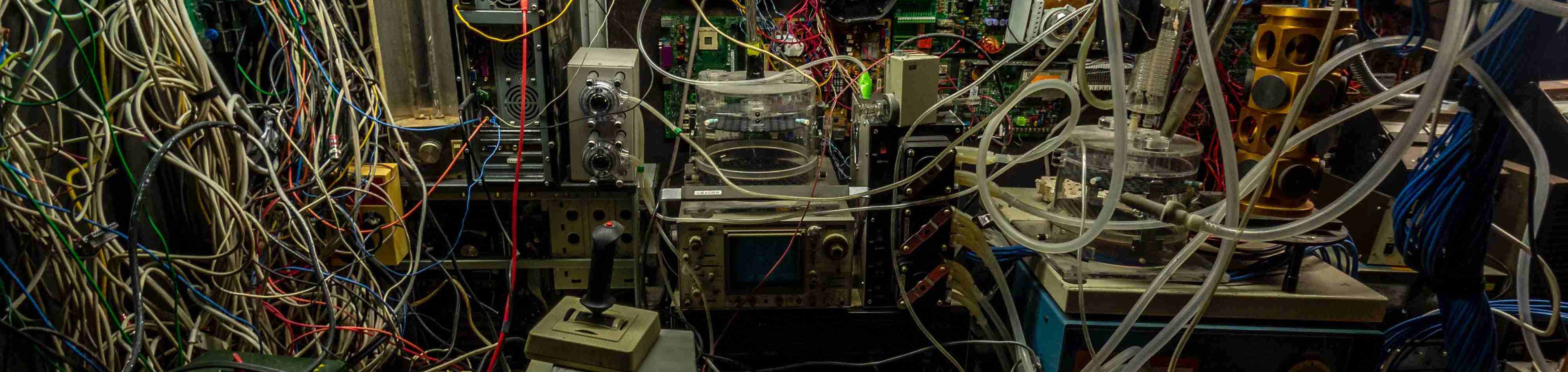 A dark photo of tubes and cables messily wired around a room